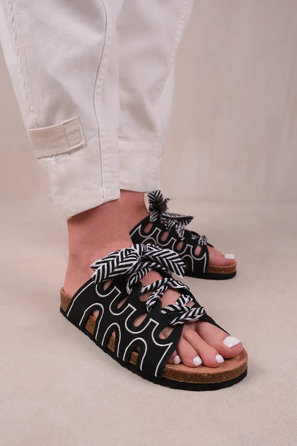 PARADOX STRAPPY FLAT SANDALS WITH PRINTED RIBBON DETAILING IN BLACK FAUX LEATHER